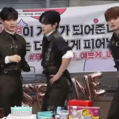 a group of young men are standing in front of a birthday cake .