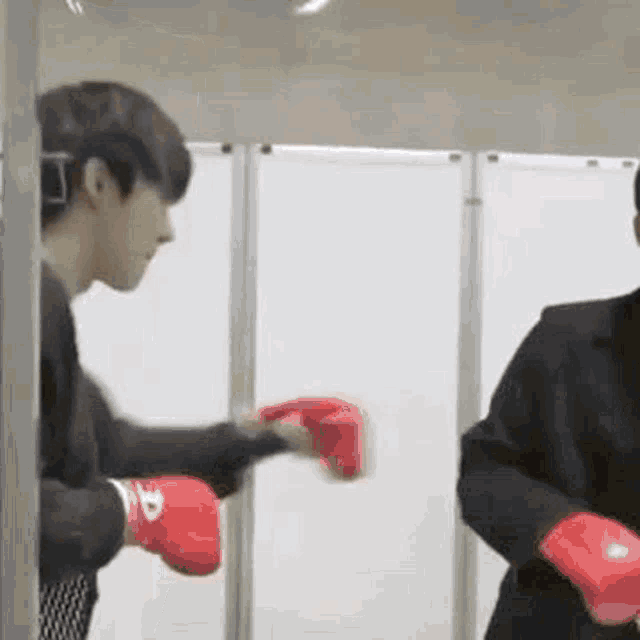a man wearing boxing gloves is standing next to another man wearing boxing gloves .