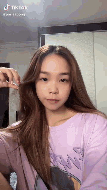 a woman in a purple shirt has a tiktok sticker on her shirt