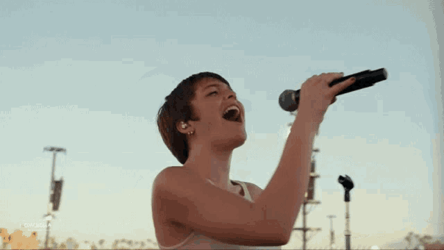a young man is singing into a microphone on a stage .