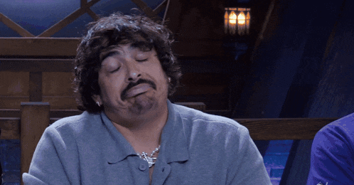a man with a beard and earrings is making a funny face with his eyes closed