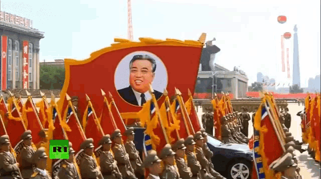 a group of soldiers marching with flags and a picture of kim jong un