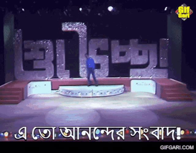 a man stands on a stage in front of a large sign that says gifgari