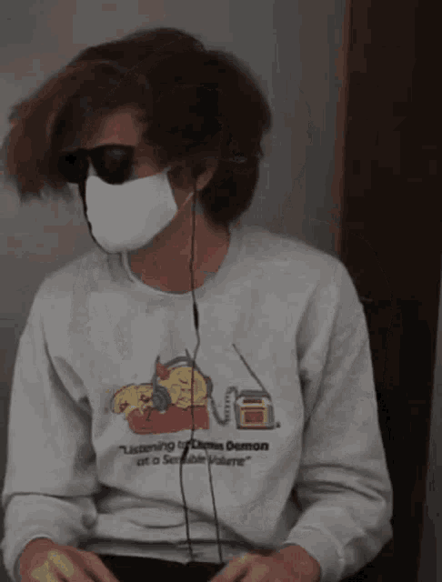 a man wearing a mask and sunglasses is wearing a sweatshirt that says listening to demon at a sensible volume