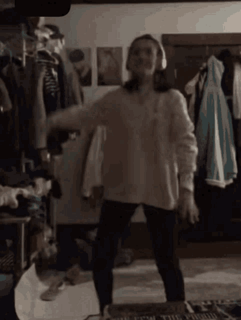 a woman wearing headphones is dancing in a room with a sign that says " you are the proud "