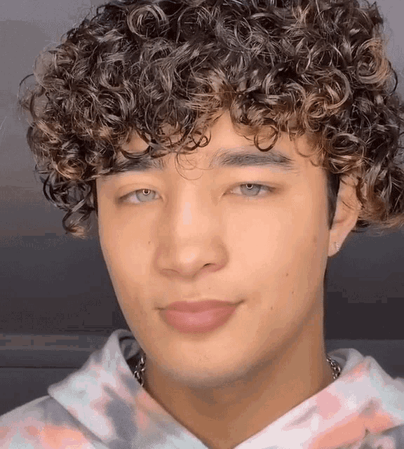 a young man with curly hair and blue eyes