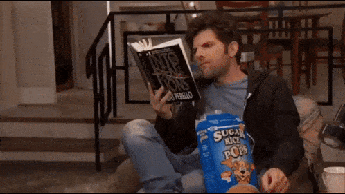 a man is reading a book while holding a bag of sugar rice chips