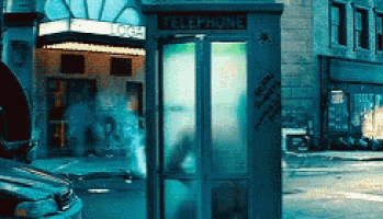 a telephone booth in a city street with a car parked in front of it