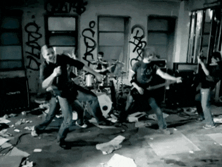 a black and white photo of a band playing in front of a wall that has graffiti on it