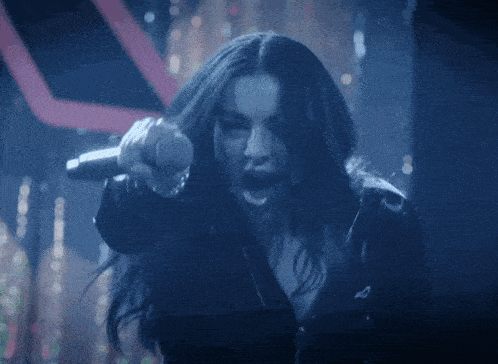 a woman is singing into a microphone and pointing