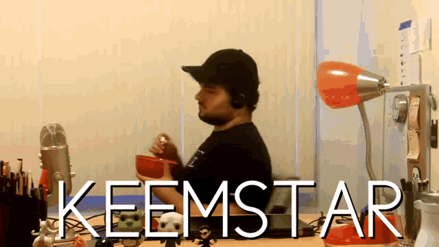 a man sitting at a desk with the word keemstar written on the bottom