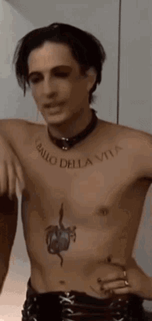 a shirtless man with a tattoo on his chest is standing in a room .