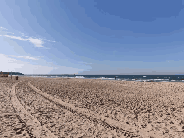 a beach with a blue sky and a few waves