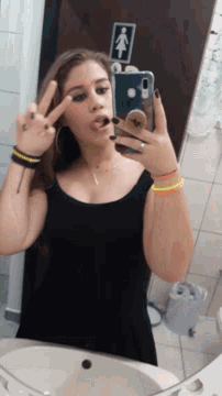 a woman is taking a picture of herself in a bathroom with a sign that says women 's restroom