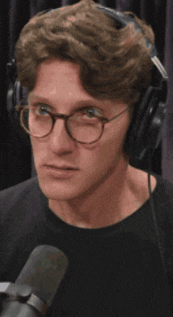 a man wearing glasses and headphones is sitting in front of a microphone