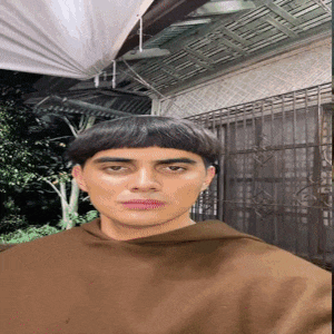 a man with a very short haircut is wearing a brown poncho