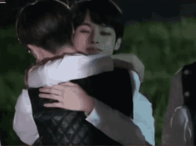a man and a woman are hugging each other in a field .