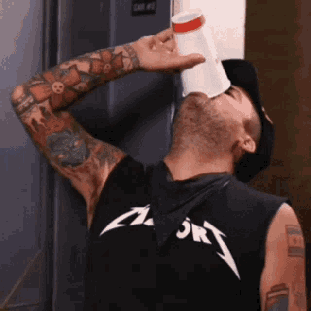 a man wearing a metallica shirt drinking from a cup