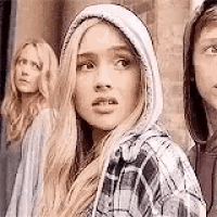 a woman in a plaid shirt with a hood is standing next to two other women in hoodies .