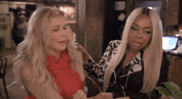 two women are sitting next to each other in a room and talking .