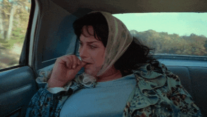 a woman with a scarf around her head is sitting in a car