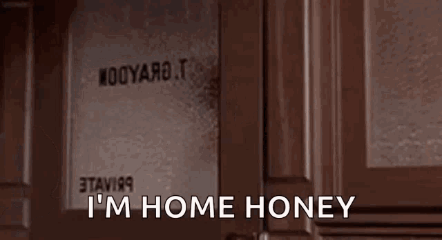 a woman is sitting in front of a door with the words `` i 'm home honey '' written on it .