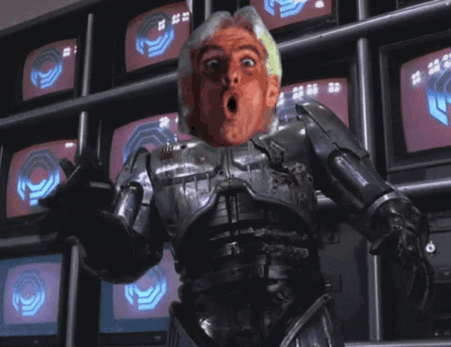 a robot with a surprised look on his face is standing in front of a wall of televisions