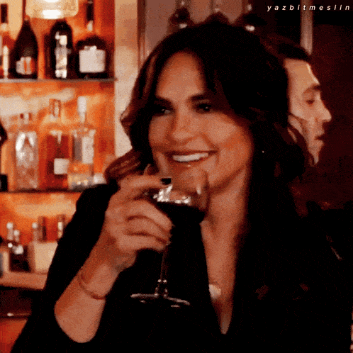 a woman is smiling while holding a glass of wine with yazbitmesiin written below her