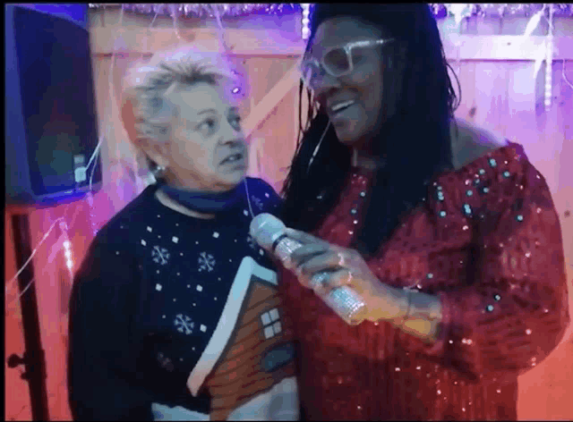 a woman is holding a microphone and talking to another woman