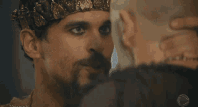 a man with a beard and a crown on his head is smiling