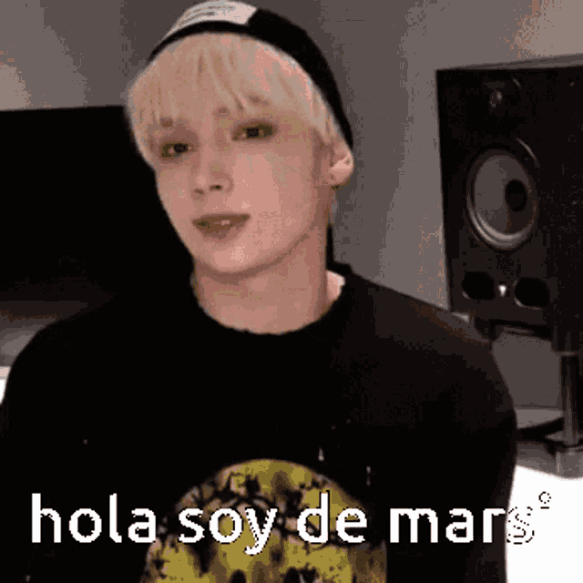 a young man wearing a black hat and a black shirt says hola soy de mars .