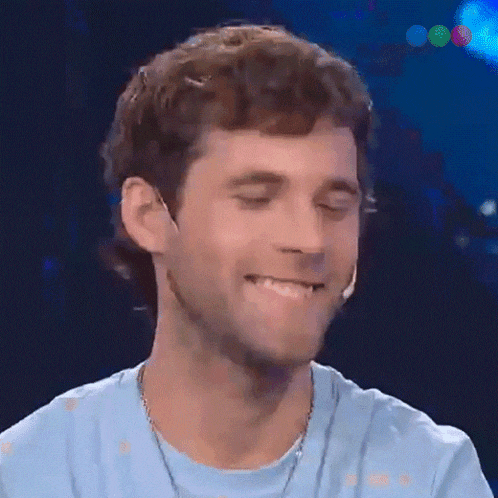 a man wearing a light blue shirt is smiling with his eyes closed .