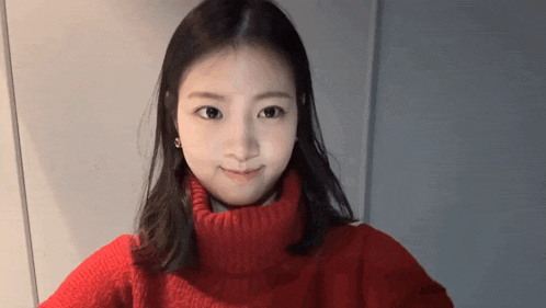 a young woman wearing a red turtleneck sweater is smiling