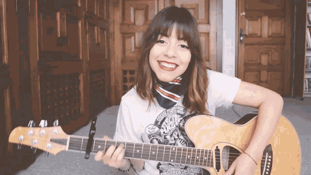 a woman is playing an acoustic guitar and wearing a shirt that says ' rolling stones ' on it
