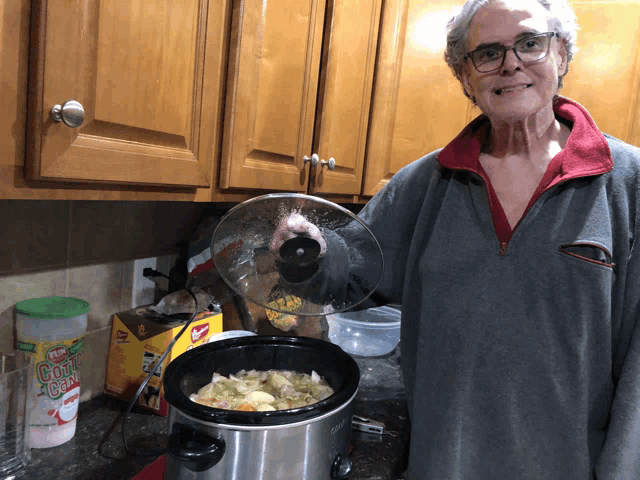 a woman is cooking in a crock pot with a box of pop corn in the background