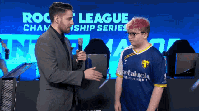 a man in a suit is talking to a man in a blue and yellow jersey that says andalucia on it