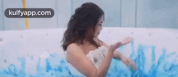 a woman is taking a bath in a hot tub covered in blue foam .