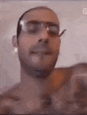 a man without a shirt is wearing glasses and smoking a cigarette in a video .