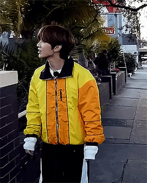 a young man wearing a yellow and orange jacket with the word salomon on the front