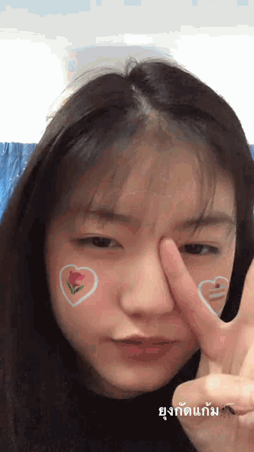 a girl with a heart and flower painted on her face is making a peace sign