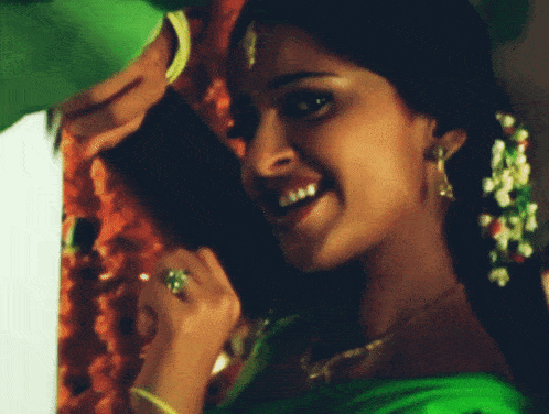 a woman in a green dress is smiling with a man in a green shirt behind her