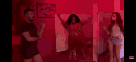 a group of people are dancing in a bathroom in a red room .