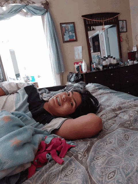a woman laying on a bed with a picture of a man on the wall