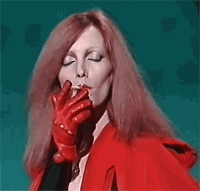 a woman with red hair is wearing a red jacket and gloves