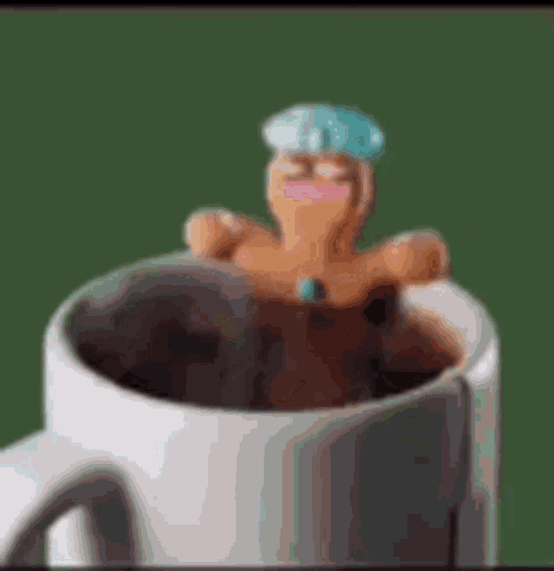 a gingerbread man is sticking out of a coffee cup .