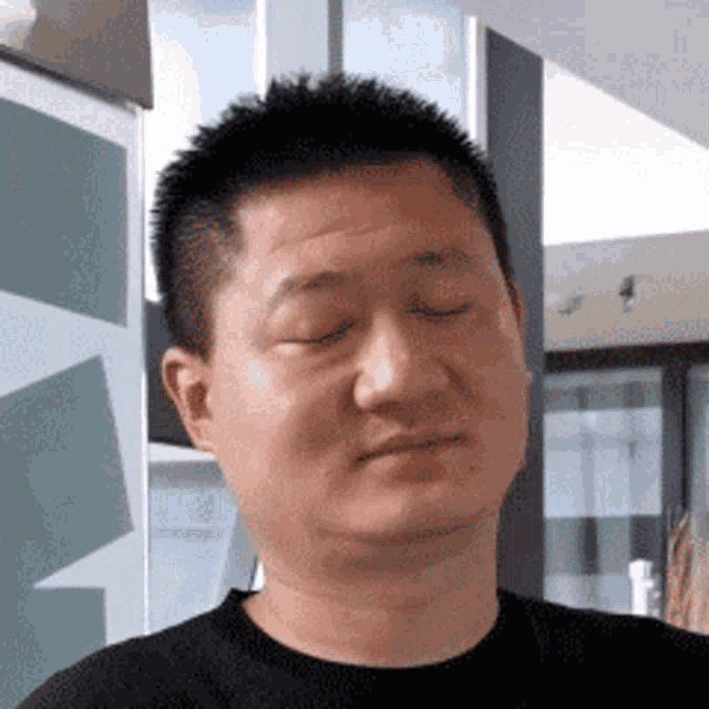 a man with his eyes closed is wearing a black sweater