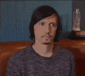 a man wearing a grey sweater is sitting in a chair