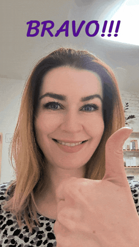 a woman is smiling and giving a thumbs up with the word bravo behind her
