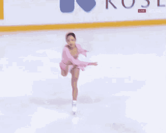 a woman in a pink dress is ice skating on a rink