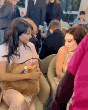 a woman is holding a cat in her lap while sitting in a chair in a crowd .